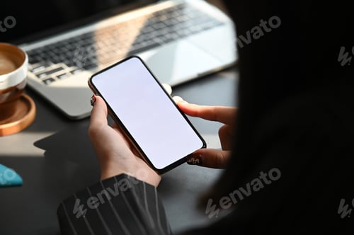 Preview: Cropped image of businesswoman's hand holding white blank screen mobile at modern working desk.
