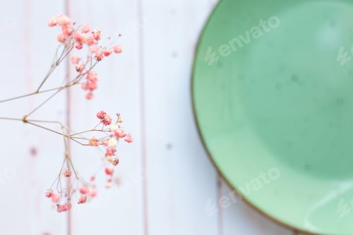 Preview: Light green ceramic plate with cute dried flowers on white wooden background. Top view
