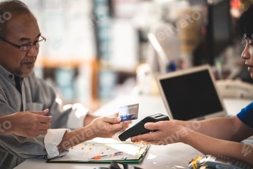 Preview: Senior customer paying garage for services and repair work using debit and credit card