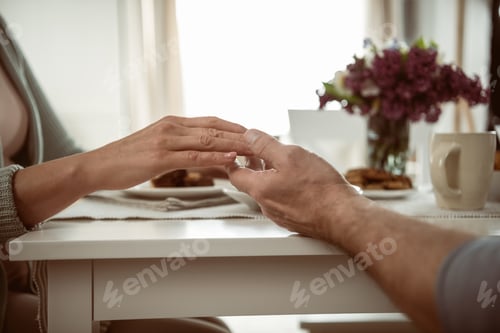 Preview: cropped view of senior couple holding hands during breakfast