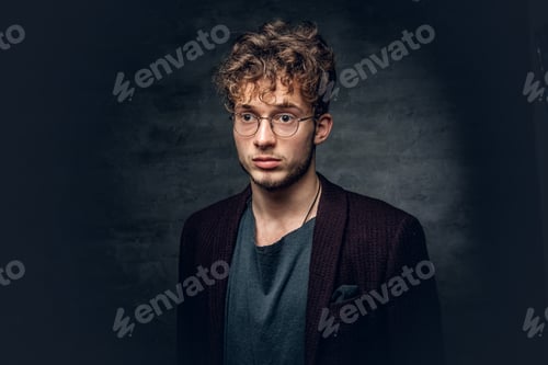 Preview: A man with curly hair dressed in a jacket and eyeglasses.