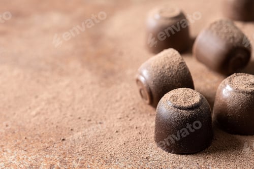 Preview: Chocolate bonbons and cocoa powder background. Close up