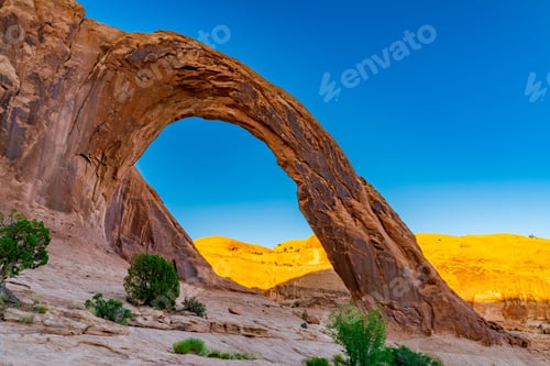 Preview: Corona Arch in Utah, USA with mountains and a blue sky in the background.