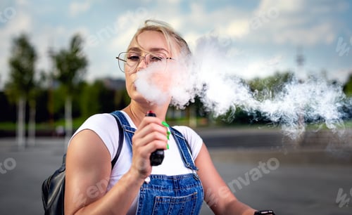 Preview: Portrait of young woman smoking an e-cigarette outdoor