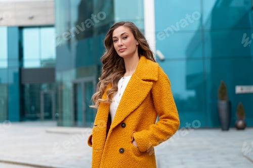 Preview: Business woman standing near corporative building outdoor dressed yellow stylish coat