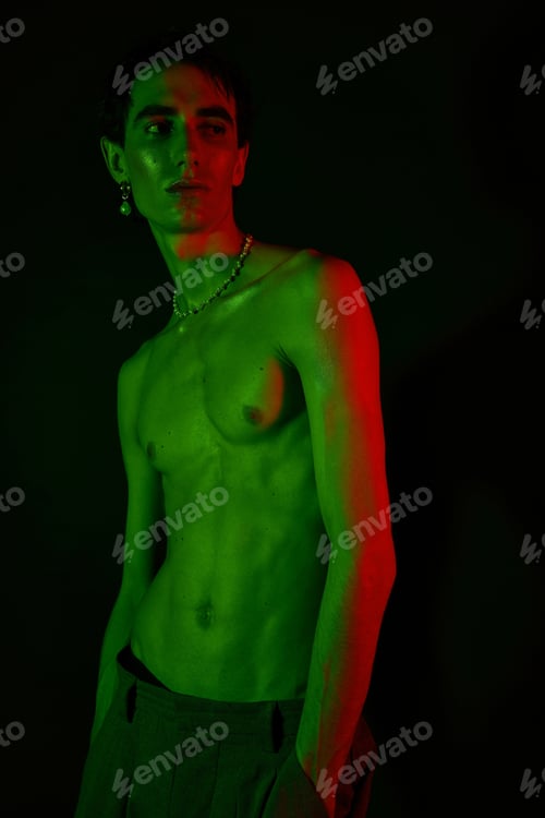 Preview: Handsome stylish man striking a pose under vibrant green and red lighting at night