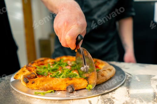 Preview: close up in a professional kitchen in pizzeria the chef cuts the pizza into pieces with a round
