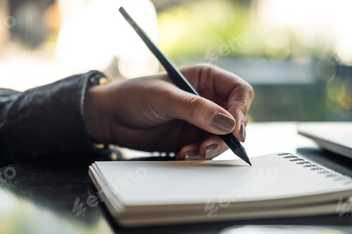 Preview: Closeup image of a woman's hands writing on notebook on the table