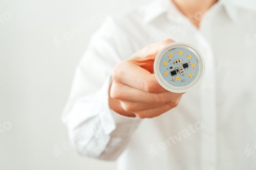 Preview: Woman in white shirt holding light bulb in hand