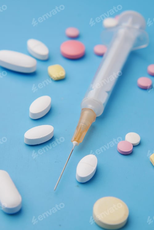 Preview: syringe and pills on blue background, close up
