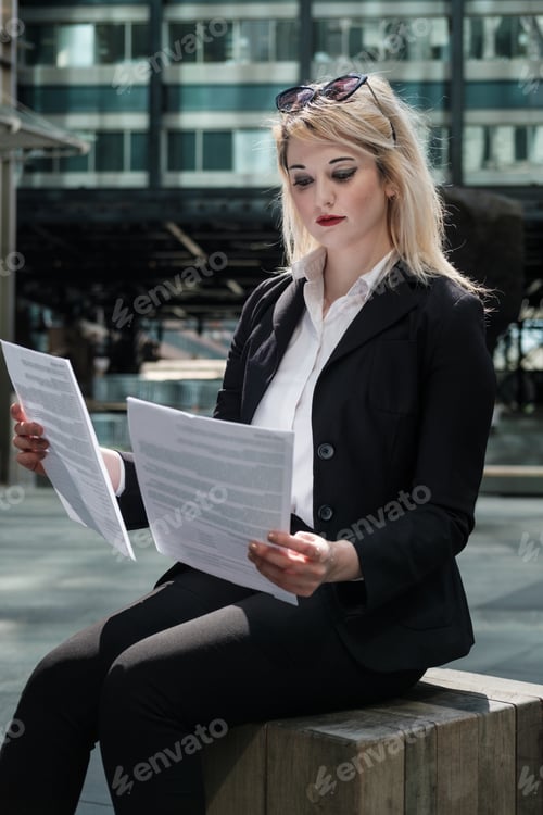 Preview: Businesswoman checking some papers outdoors.