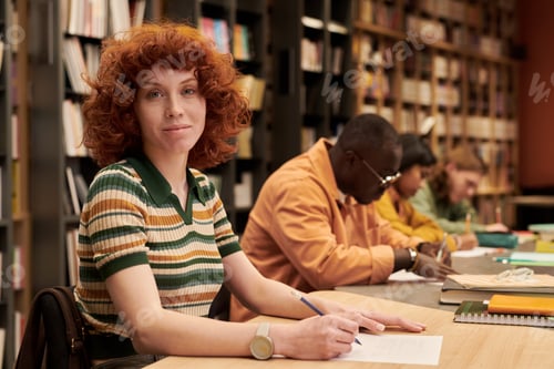 Preview: Portrait of Young Woman Studying in Library with Diverse Group