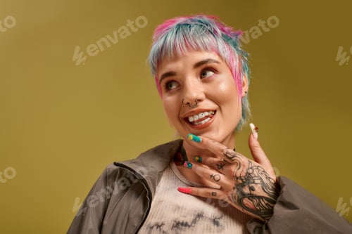 Preview: A young woman with vibrant dyed hair smiles playfully in a bright studio space