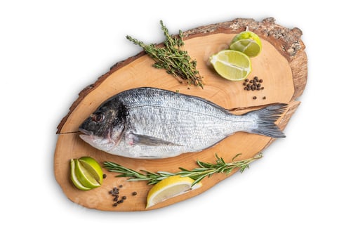 Preview: Fresh raw dorada on wooden cutting board, top view
