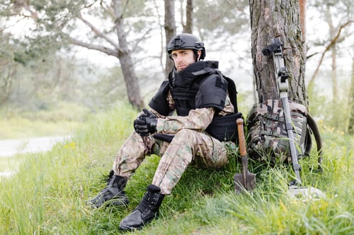 Preview: A man in bulletproof vest sits in the forest near a metal detector and a military backpack