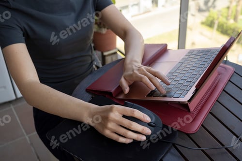 Preview: Woman works from her balcony using an ergonomic vertical mouse and a laptop stand