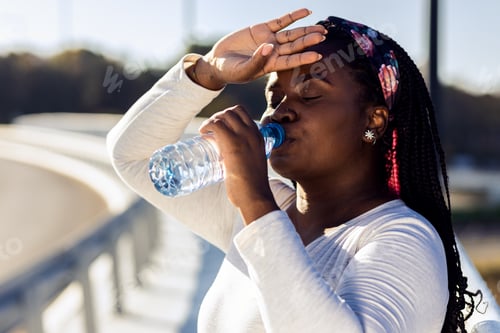 Preview: Young plus size women resting after running drinking water.