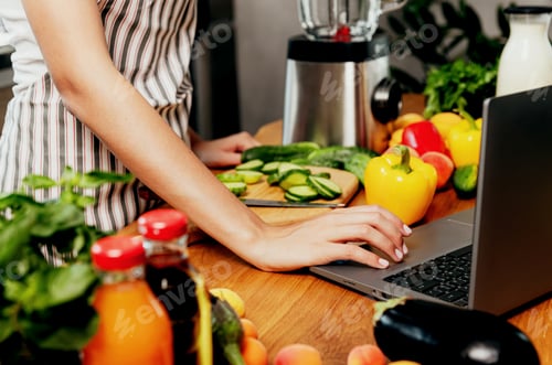 Preview: Female hand using laptop at kitchen. Food delivery, mobile dieting app