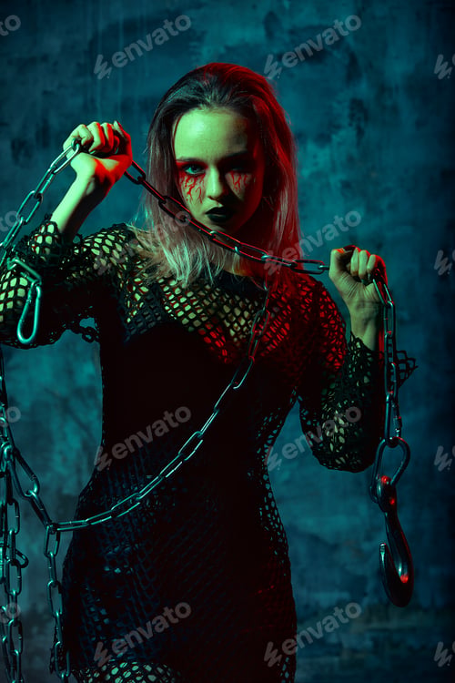 Preview: close up portrait of beautiful sexy witch with halloween makeup. red and black face painting. chain