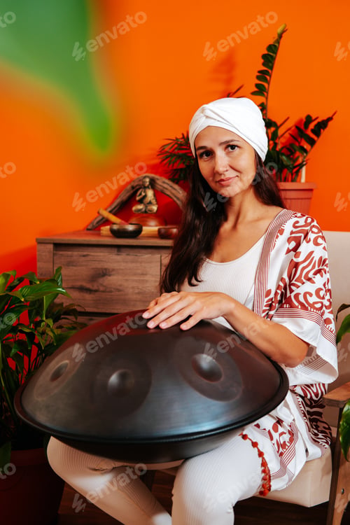 Preview: Beautiful young woman in white turban playing handpan musical instrument. Sound healing concept.