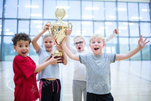 Preview: Happy pupils holding trophy in gym