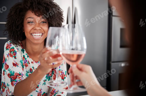 Preview: Two Female Friends Making Toast As They Drink Wine At Home Standing By Kitchen Island