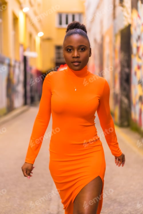 Preview: Fashionable urban style with a black African girl in an orange dress and black heels