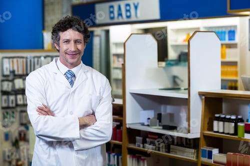Preview: Mature pharmacist in lab coat standing at pharmacy counter with shelves under BABY sign, copy space