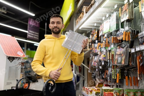 Preview: happy customer in a hardware store with a grill grate and a barbecue in their hands are preparing