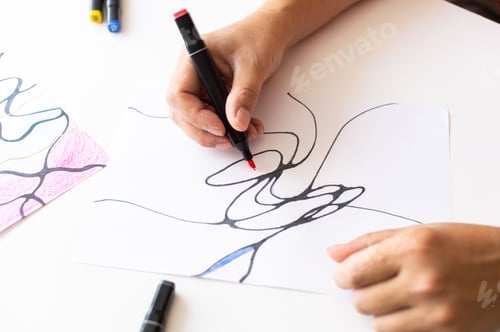 Preview: Hands drawing abstract lines with a black marker on white paper