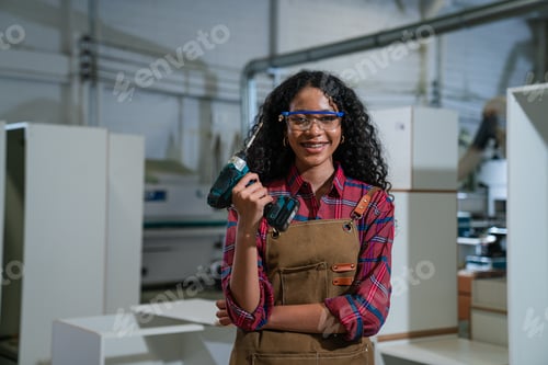 Preview: Young woman working as carpenter in a small carpentry workshop.