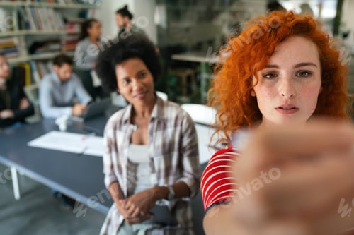 Preview: Diverse group of happy employees analyzing reports with digital device, working together in office