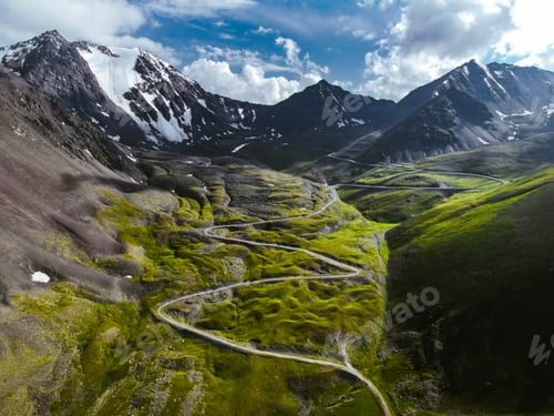 Preview: Aerial view of steep winding road and green alpine valley