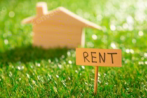 Preview: Wooden toy house with rent sign on grass