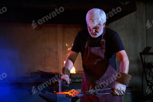 Preview: Caucasian aged blacksmith hitting molten metal with hammer