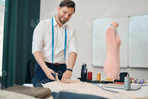 Preview: Smiling dressmaker preparing patterns for new clothes