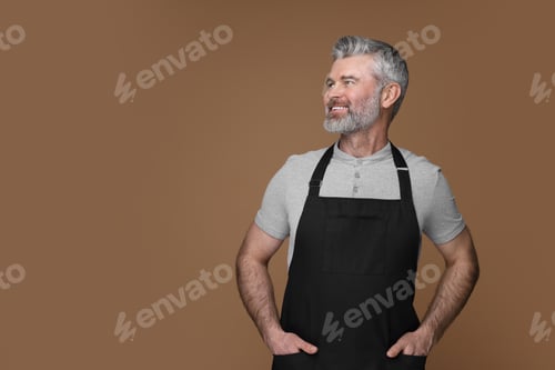 Preview: Happy man wearing kitchen apron on brown background. Mockup for design