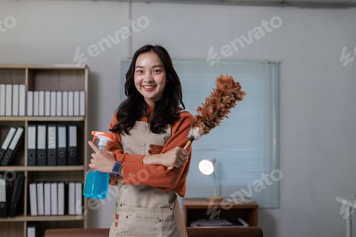 Preview: Happy asian woman holding cleaning spray and duster