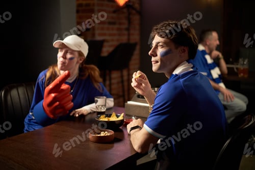 Preview: Young Caucasian Man and Woman Watching Soccer Game and Cheering Indoors