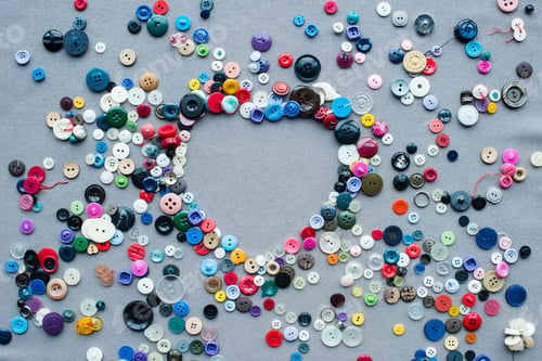 Preview: top view of colorful buttons heart shaped frame on grey cloth background