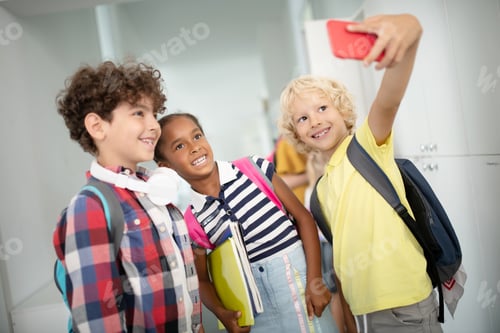 Preview: Cheerful pupils smiling while making selfie on school break