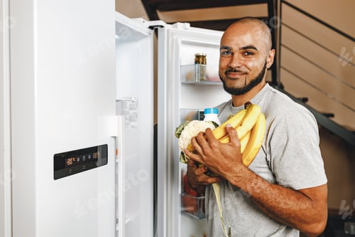 Preview: African american man taking food from a fridge in his house