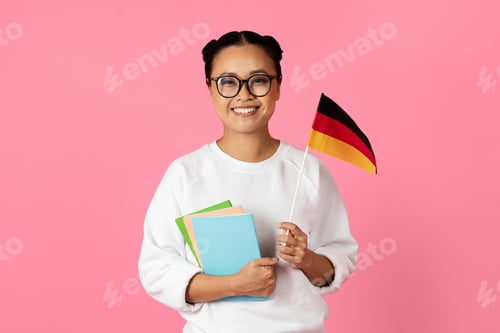 Preview: Young woman holding German flag and notebooks against a pink background
