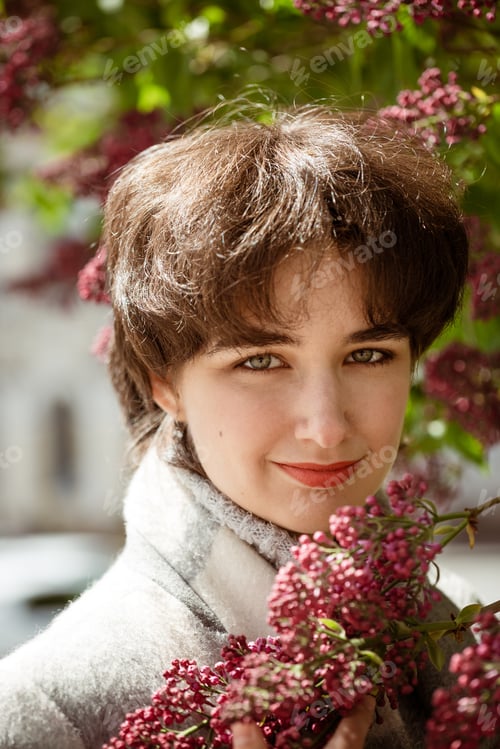 Preview: Portrait of a young woman in a lilac bush on a sunny spring day