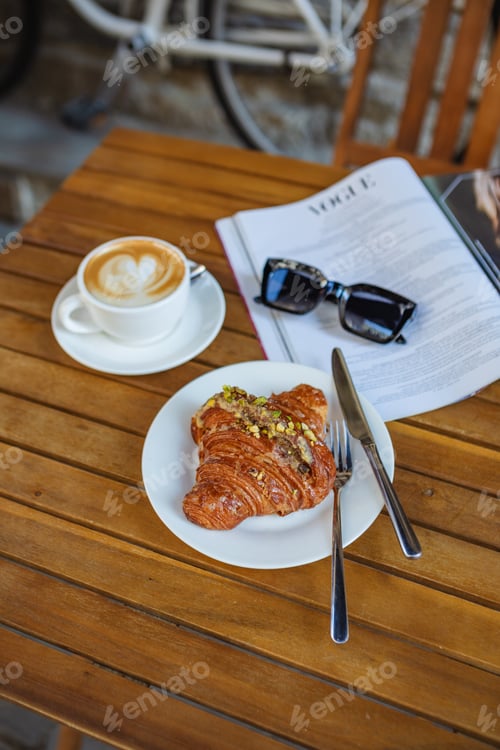 Preview: Morning coffee and croissant with reading material