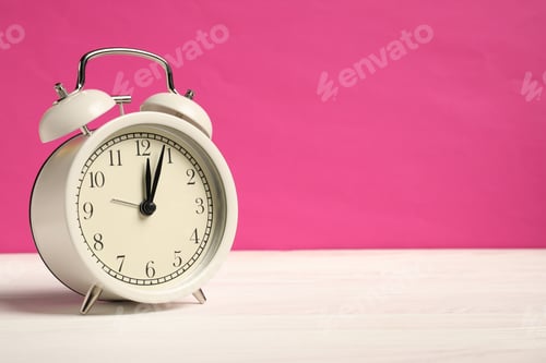 Preview: One alarm clock on white wooden table against bright pink background, space for text