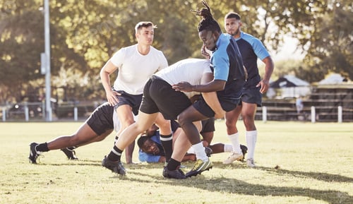 Preview: Caucasian rugby player attempting to tackle an opponent during a rugby match outside on the field.