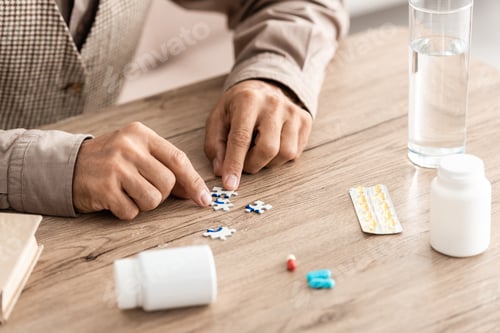 Preview: cropped view of retired man matching puzzle pieces on table