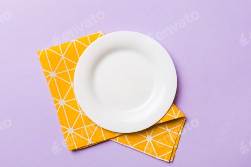 Preview: Top view on colored background empty round white plate on tablecloth for food