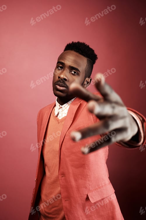 Preview: Fashion Portrait of Young Black Man in Pink Suit with Outstretched Hand